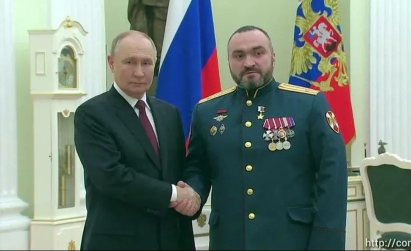 Vladimir Putin shaking hands with Major Marat Tibilov.