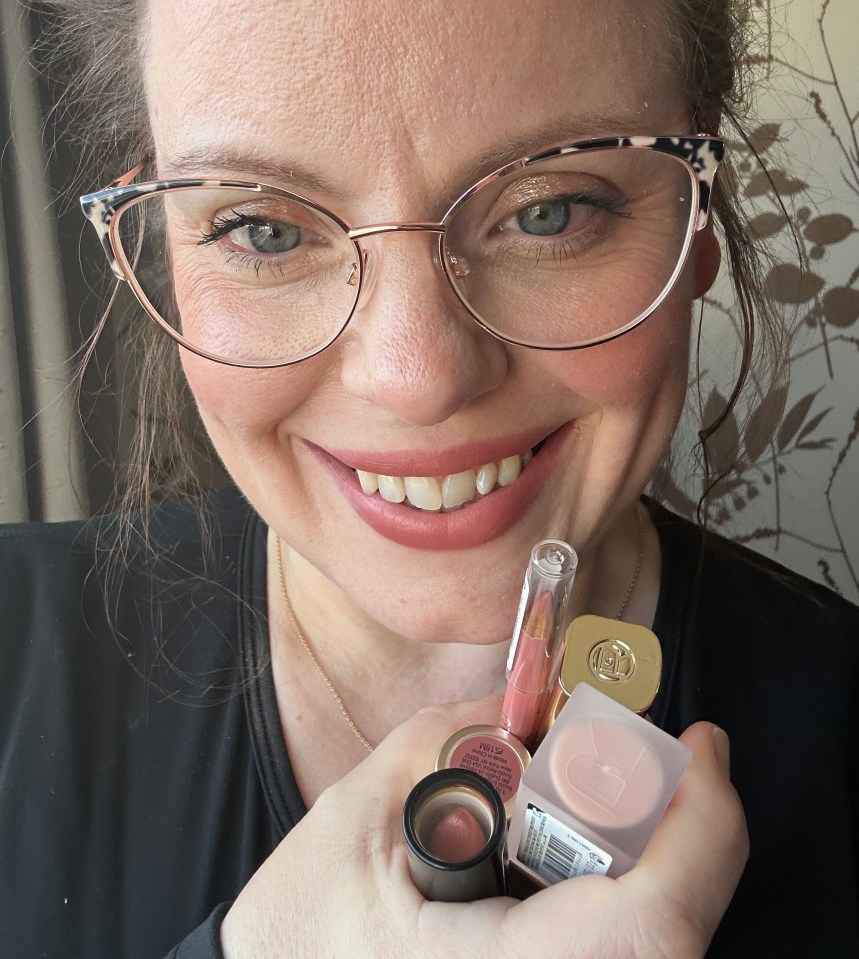 Woman holding several tubes of lipstick.