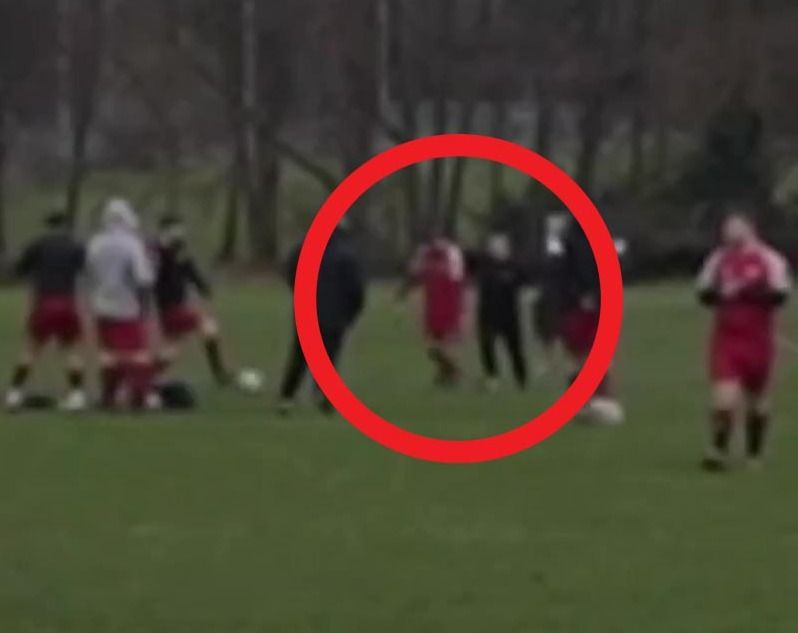 A woman hitting a football player on a field.