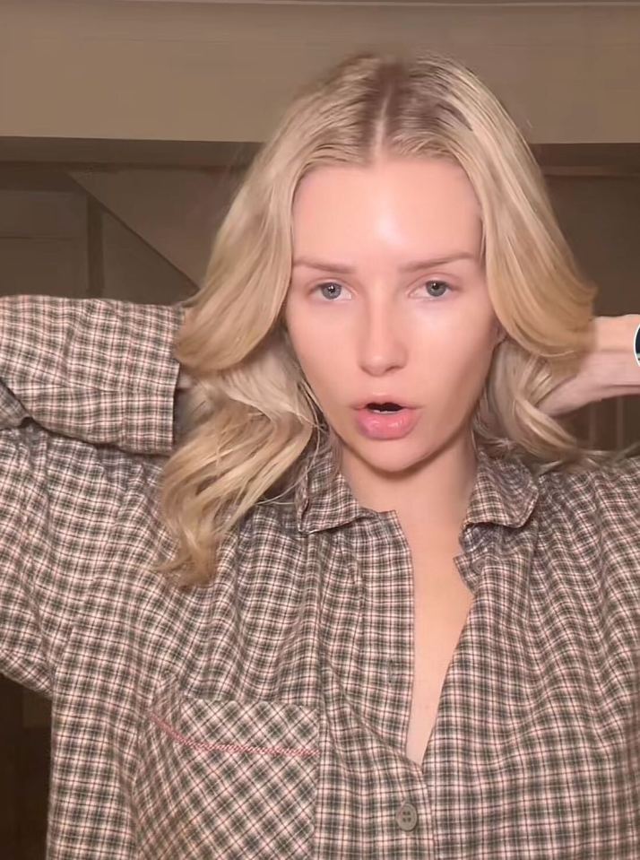 Woman with blonde hair adjusting her plaid shirt.