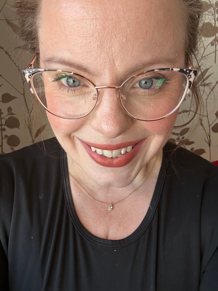 Close-up selfie of a woman wearing glasses and a necklace.
