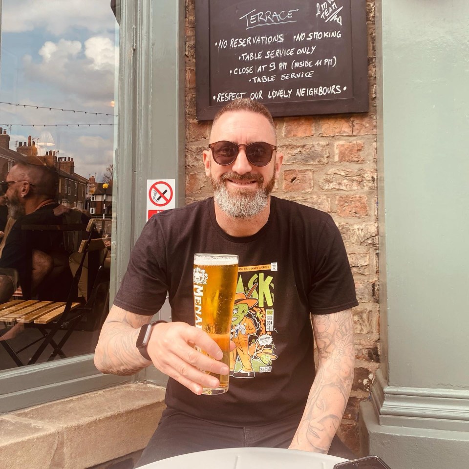 Man holding a pint of beer outside a pub.