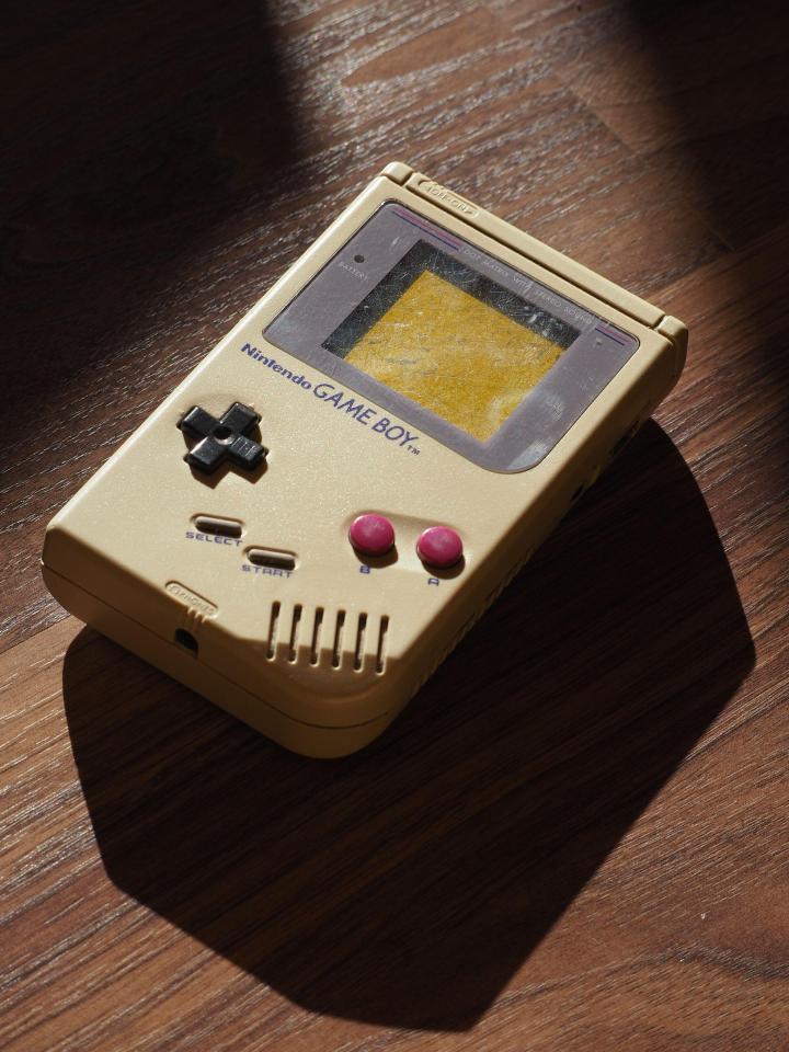 A worn Nintendo Game Boy on a wooden surface.