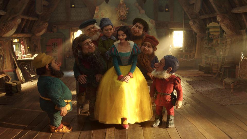 Snow White with seven dwarfs in a rustic room.