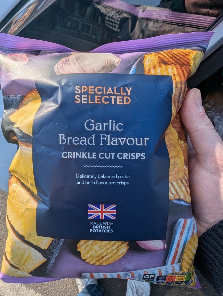Bag of Specially Selected Garlic Bread Flavour Crinkle Cut Crisps.