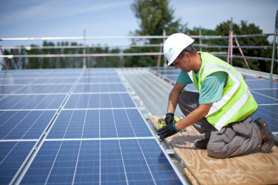 Worker installing solar panels on a roof.
