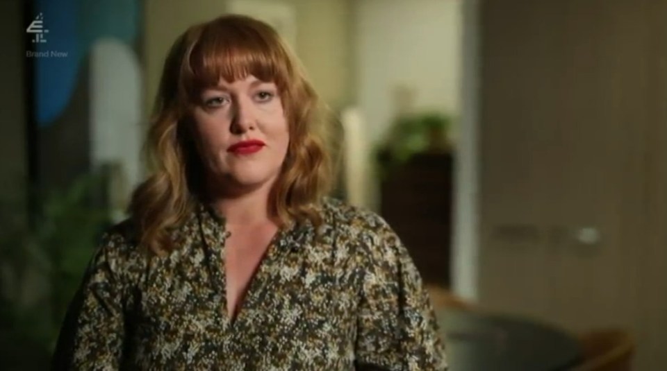Screenshot of a woman with red hair wearing a patterned blouse.