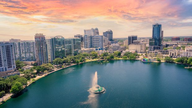 Aerial view of Orlando skyline at sunset, featuring Lake Eola and its fountain.