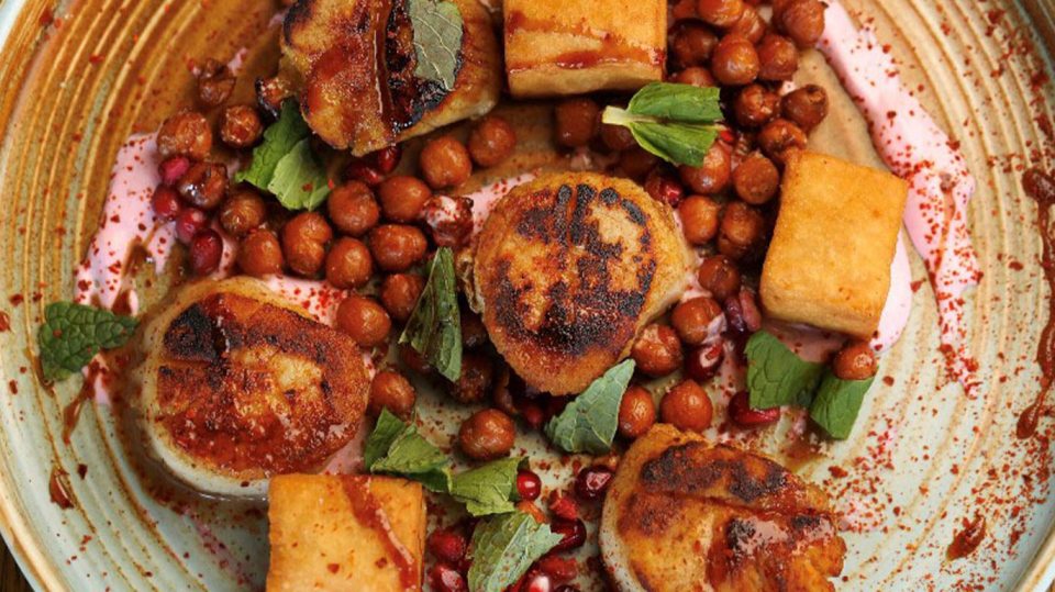 Seared scallops with chickpeas, fried potatoes, pomegranate seeds, and mint.