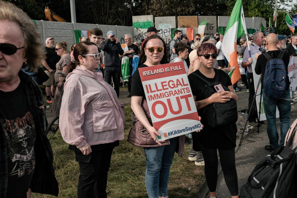 Anti-immigration protesters holding signs at a rally.