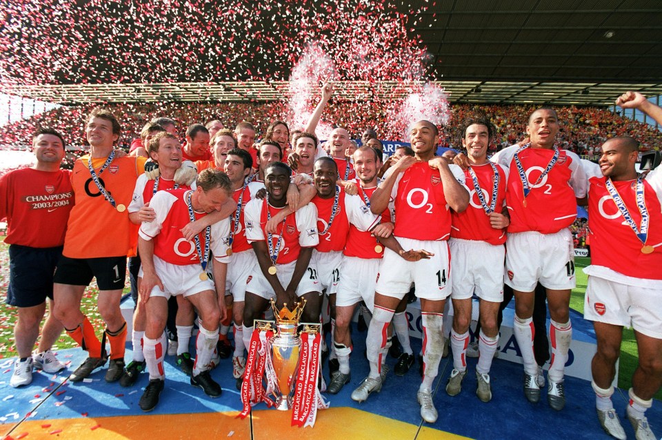 Arsenal team celebrating Premier League victory with trophy.