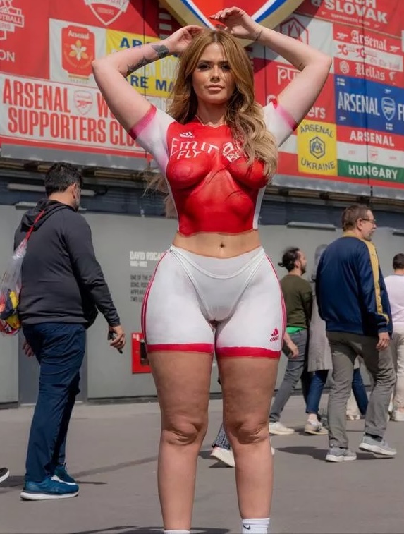 Woman in Arsenal body paint at a football stadium.