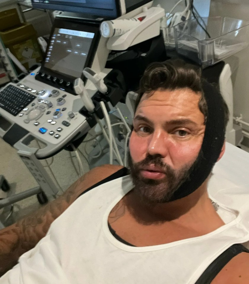 Man in hospital wearing a jaw support, next to ultrasound machine.