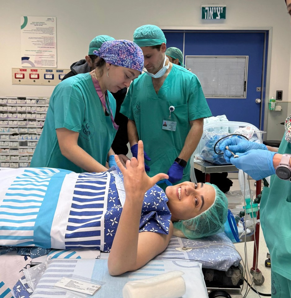 A young woman undergoing surgery, giving a thumbs up.