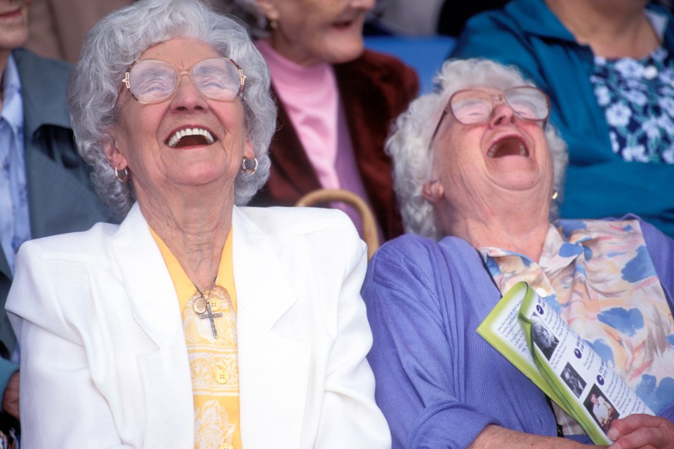 Two elderly women laughing at a pensioners' event.