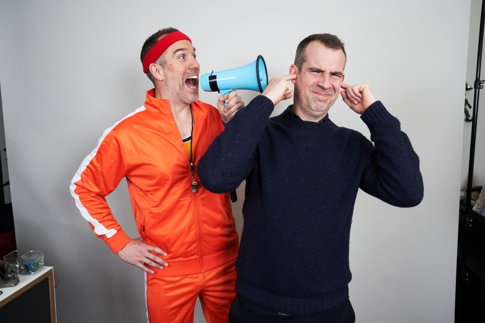 Photo of two men, one in an orange tracksuit shouting into a megaphone at the other, who is covering his ears.