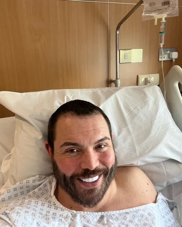 Selfie of a man smiling in a hospital bed.