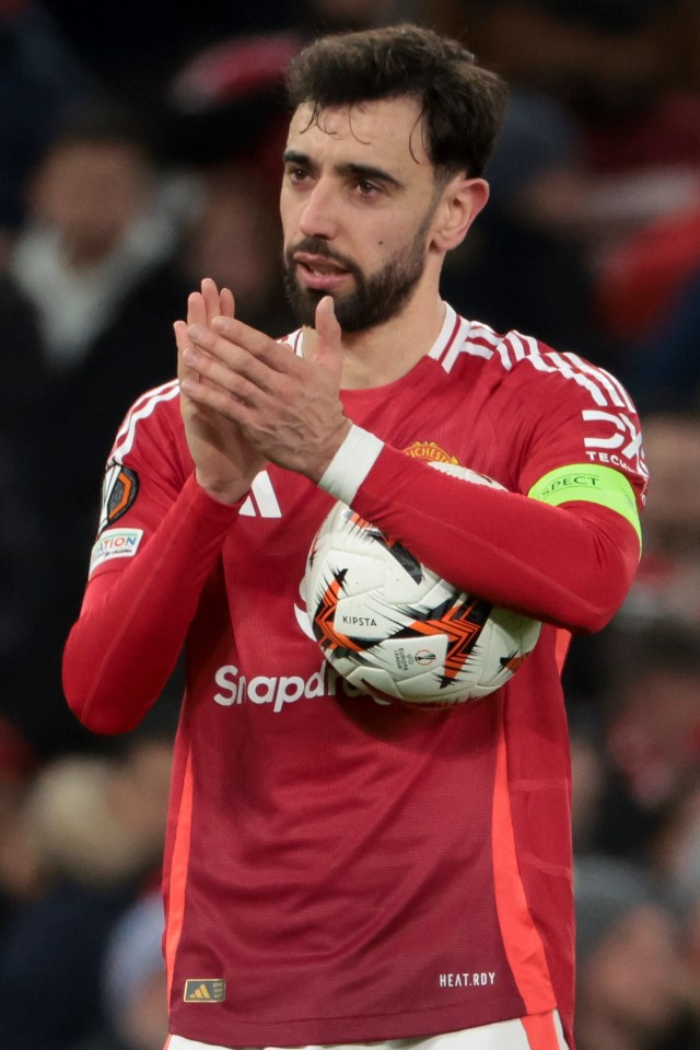 Bruno Fernandes of Manchester United applauds fans while holding a soccer ball.