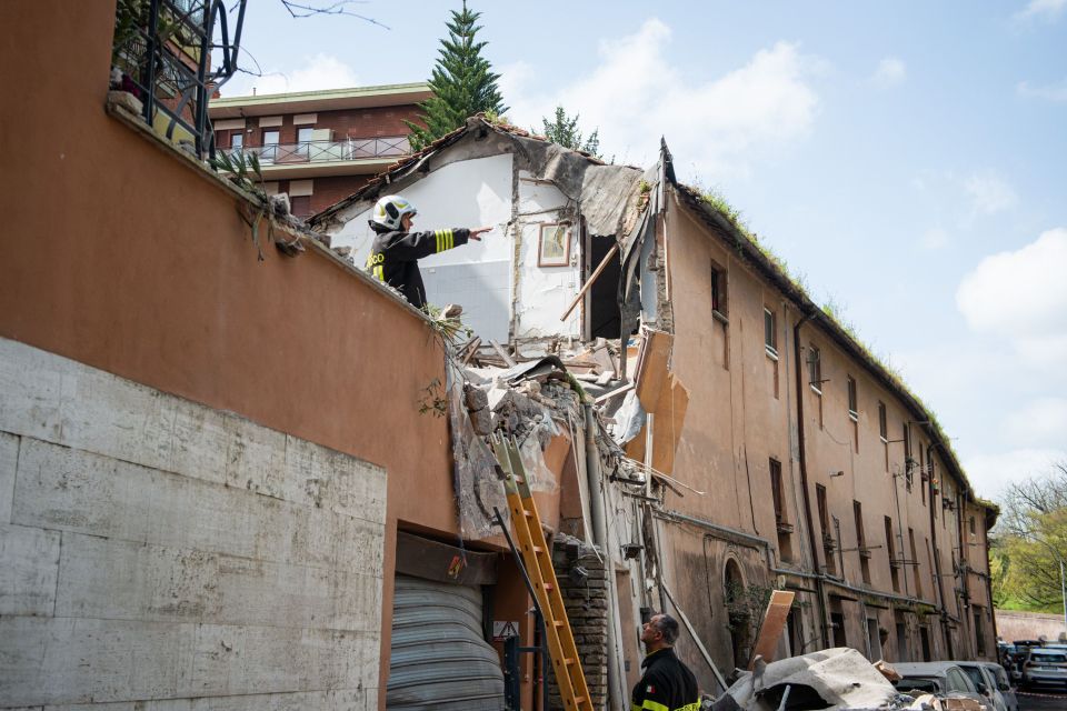 A building partially collapsed after a gas leak, with firefighters assessing the damage.