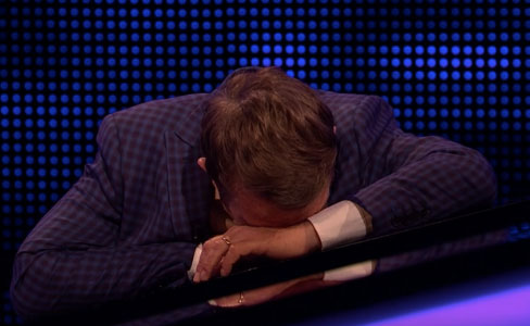 A man with his head resting on a table.