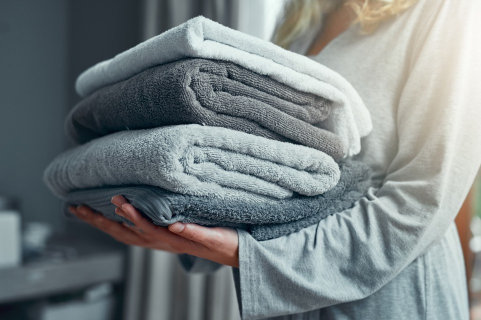 Woman holding a stack of folded towels.