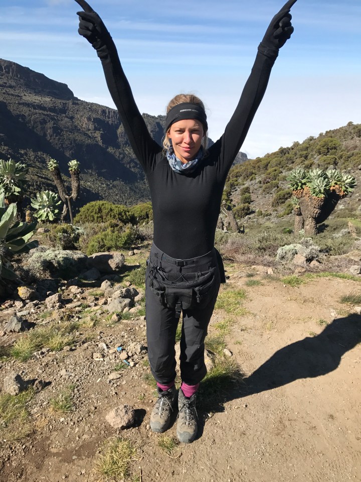 Woman hiker with arms raised on mountain path.