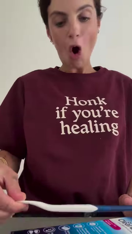 Woman holding a tongue cleaner, wearing a shirt that says "Honk if you're healing".