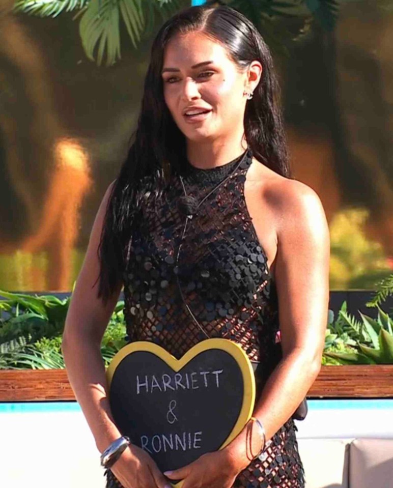 Olivia Hawkins holding a heart-shaped sign that says "Harriett & Ronnie" on Love Island.