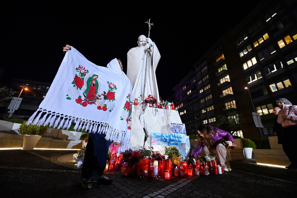 A Guatemalan devotee prays before a statue of Pope John Paul II outside a hospital in Rome.