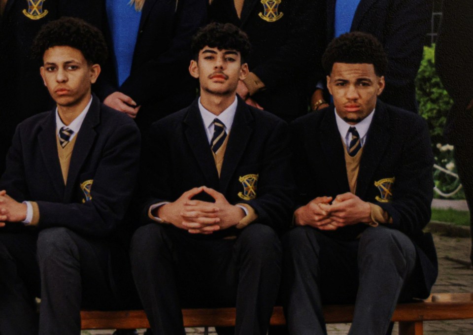 Three male students in school uniforms sitting together.