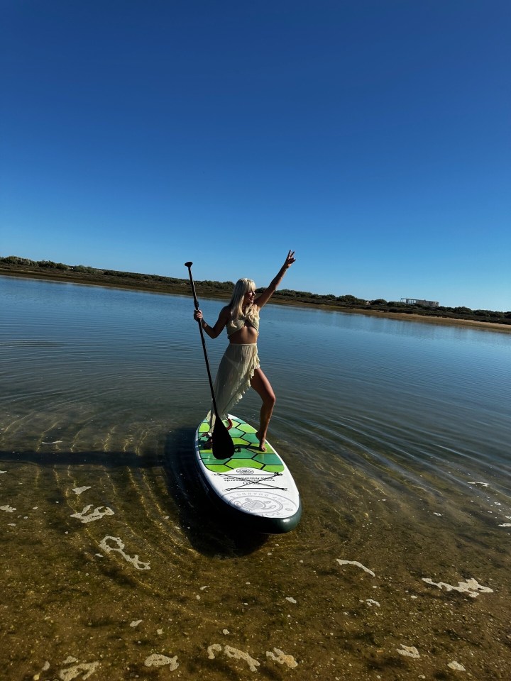 Woman paddleboarding in shallow water.