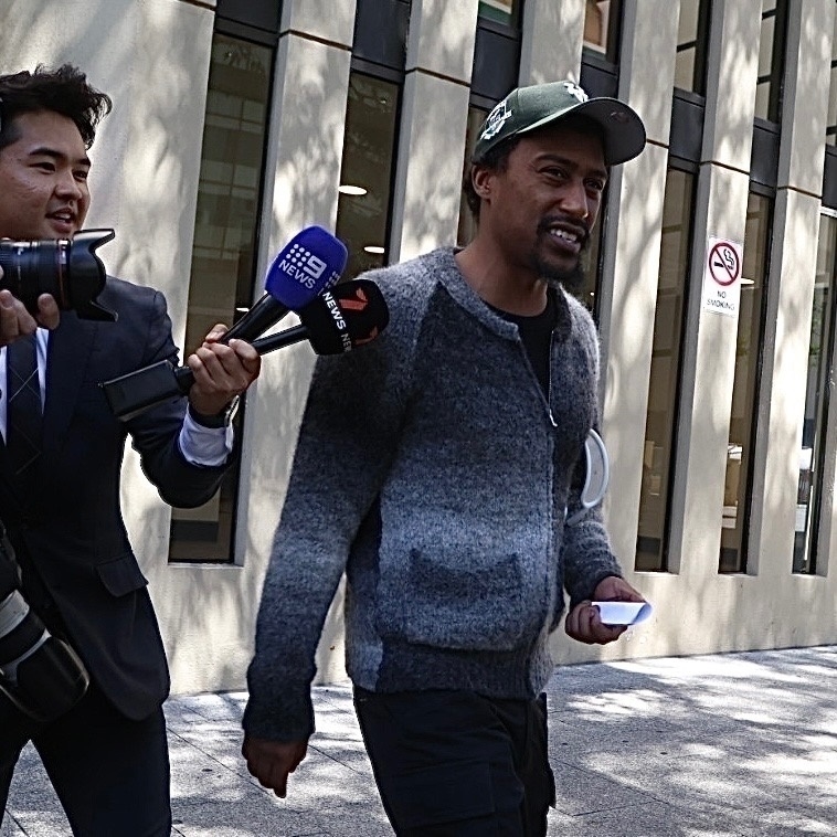 Yung Filly leaving a law court, surrounded by reporters.