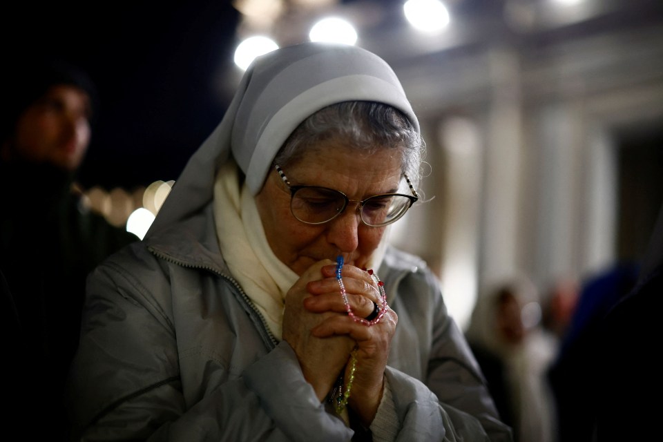 A nun prays with a rosary.