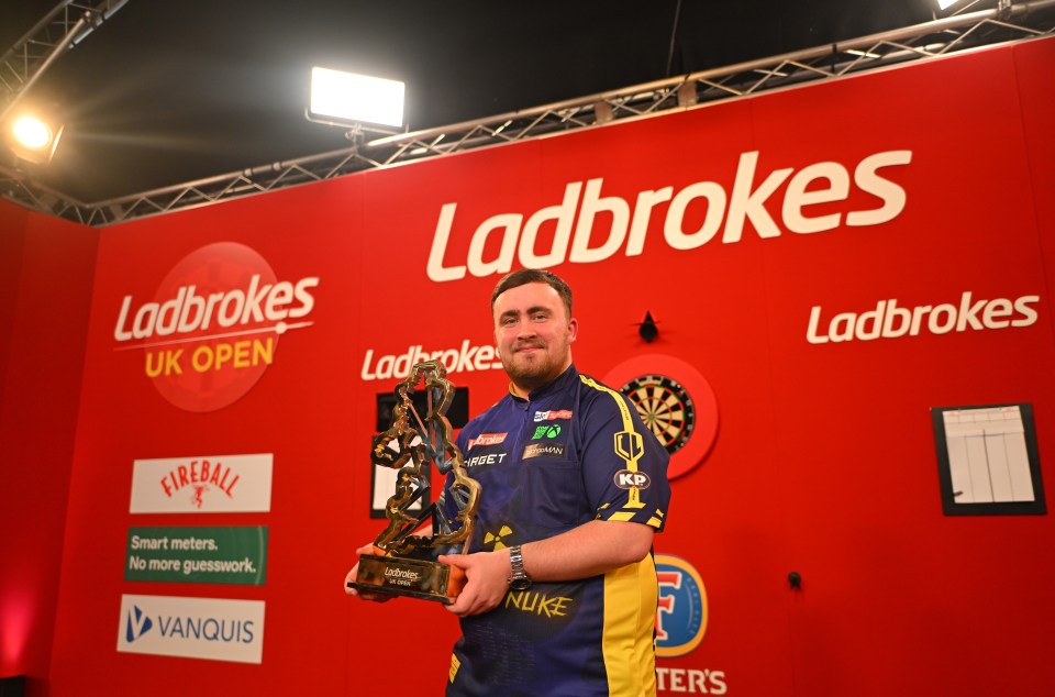 Luke Littler holding the Ladbrokes UK Open trophy.