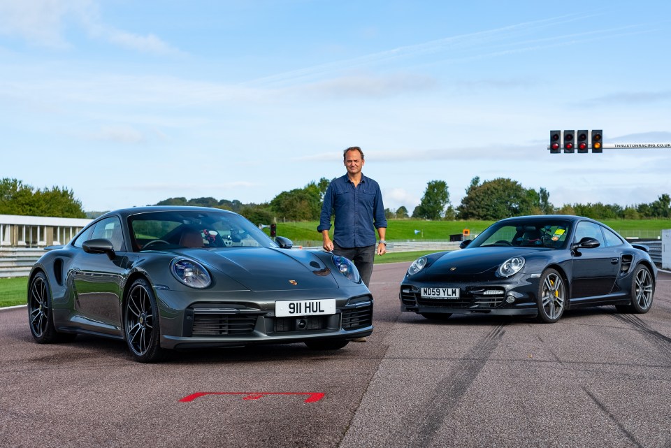 Ben Collins, former Top Gear Stig, standing between two Porsches on a racetrack.