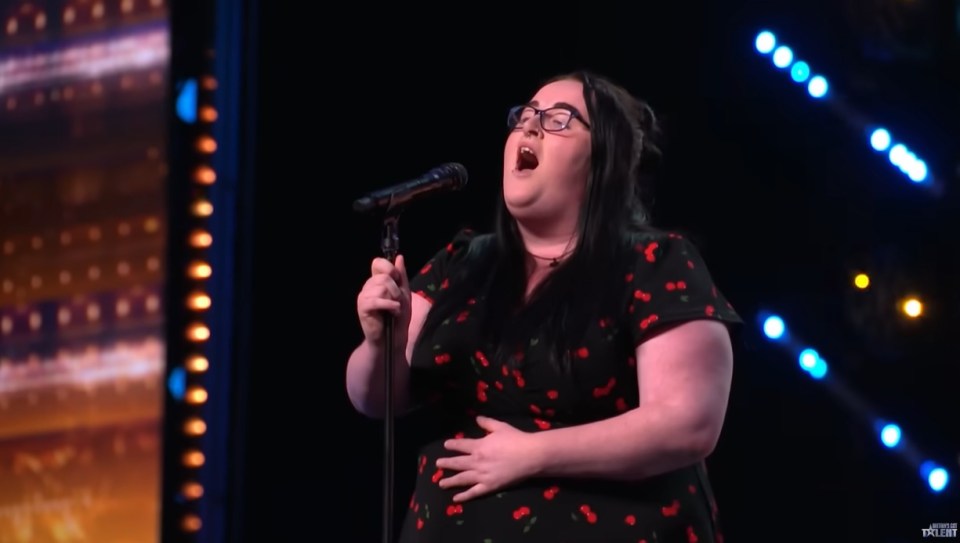 A woman singing into a microphone on a stage.