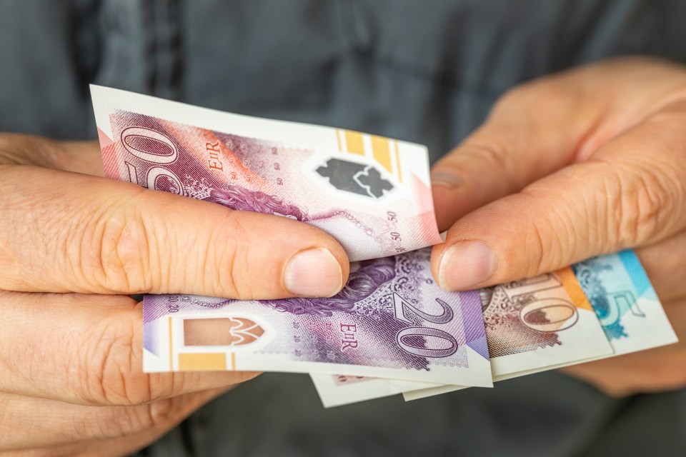 Hands holding British pounds.