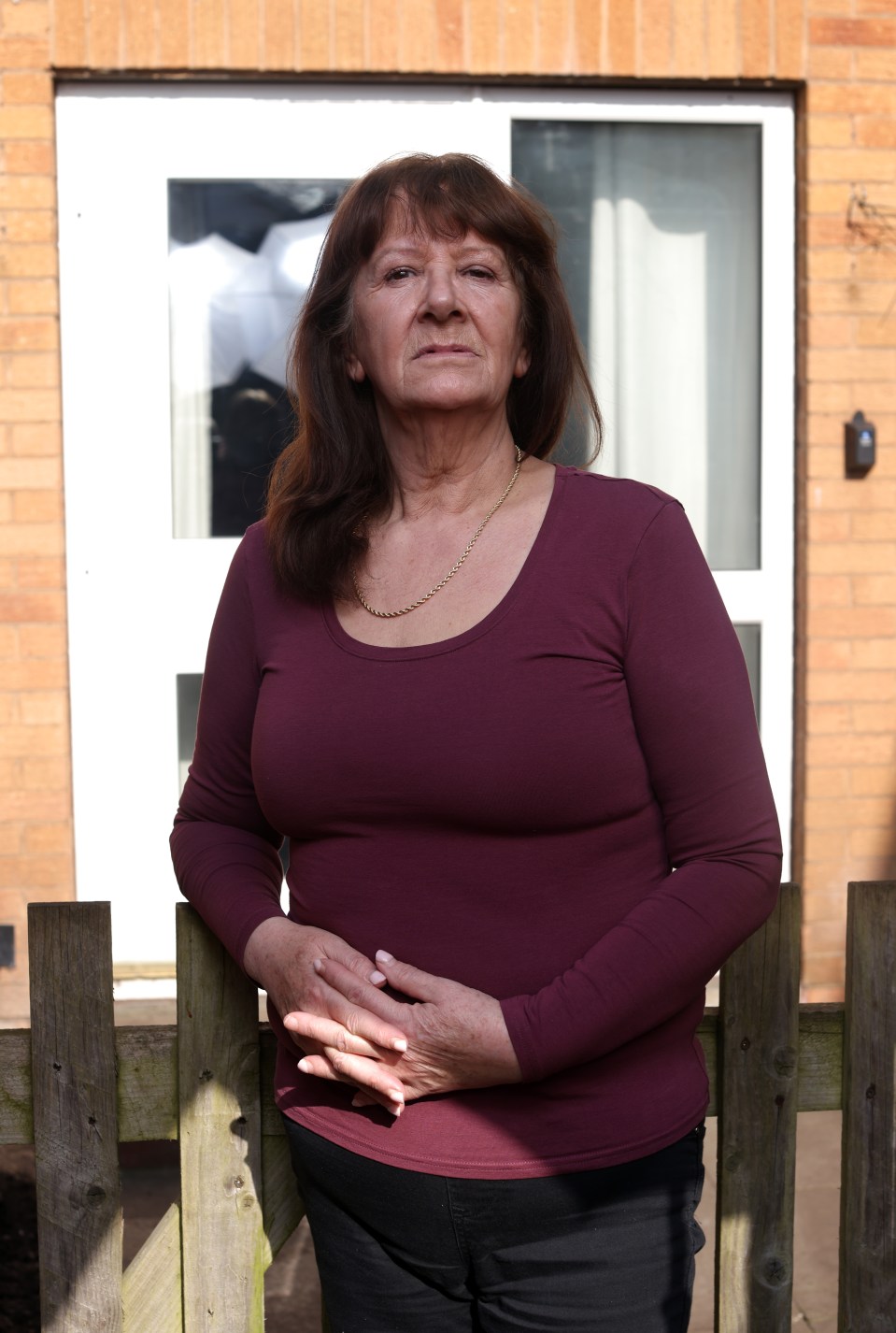 A heartbroken pensioner stands outside her home.