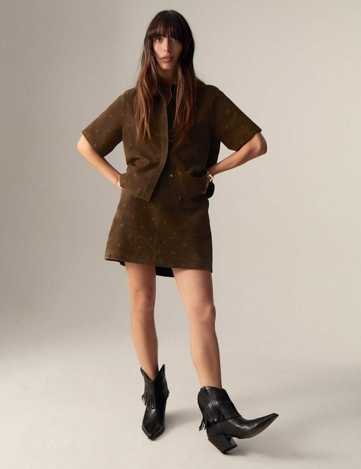 Model wearing a brown suede shirt and skirt set and black fringed boots.