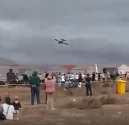 Small plane flying over a crowd of spectators.