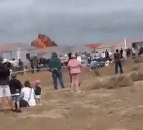Plane crash landing in a field with spectators watching.