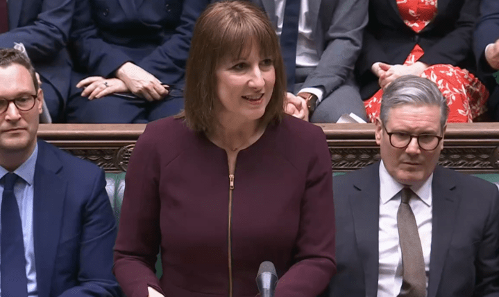 Woman speaking at a podium flanked by two men.