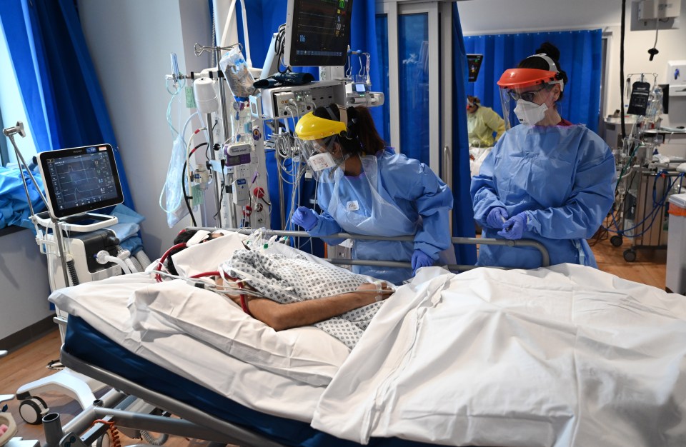 Hospital patient in bed with medical staff.