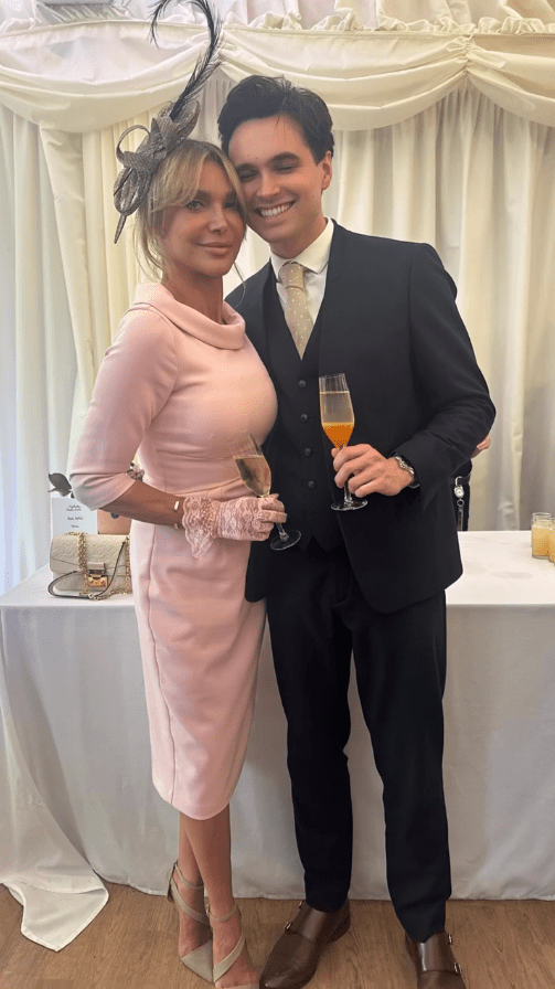 Woman in pink dress and man in suit holding champagne flutes.