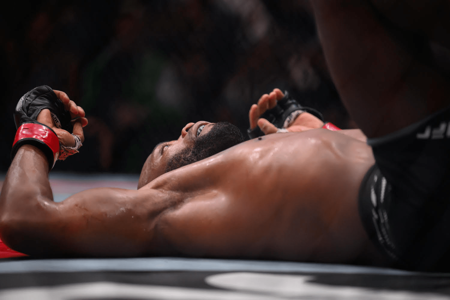 A mixed martial arts fighter lying on the ground after a match.