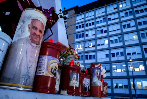 Votive candles with images of religious figures outside a hospital.