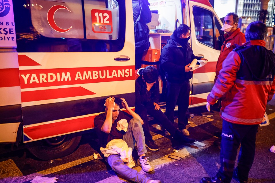 Injured protesters receiving medical treatment near an ambulance.
