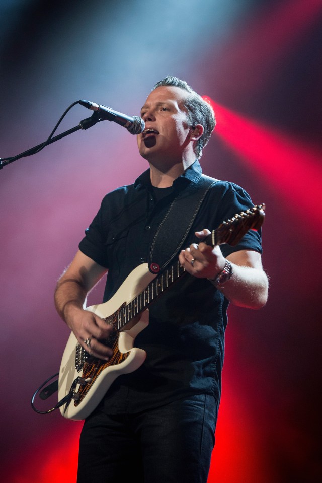 Jason Isbell performing on stage with a guitar.