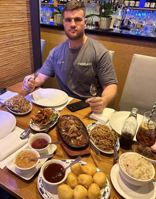 Man at a Chinese restaurant table with many dishes.