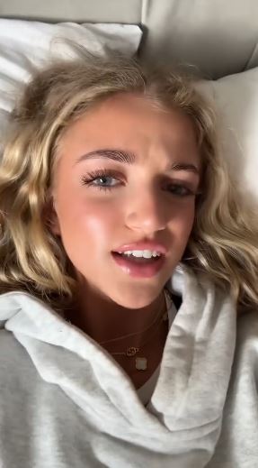 Close-up of a young woman with blonde hair wearing a gray hoodie.